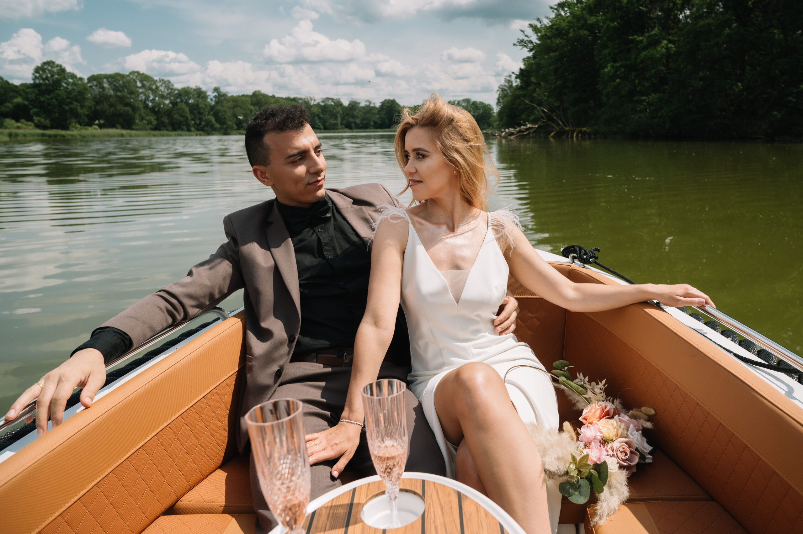 Para młoda w łódce podczas romantycznego rejsu, trzymająca się za ręce.